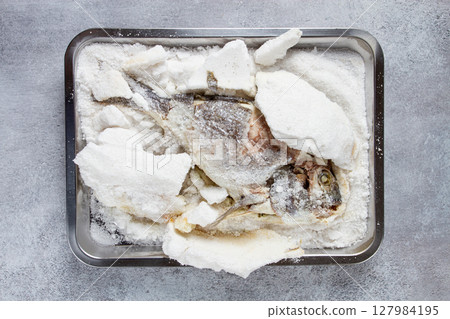 Baked Dorado fish, in salt on a baking sheet, top view, homemade, no people. 127984195