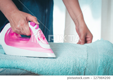 Ironing clothes at home, in a bright room, with natural light, female hands, Ironing clothes at home, in a bright room, with natural light, female hands, 127984200