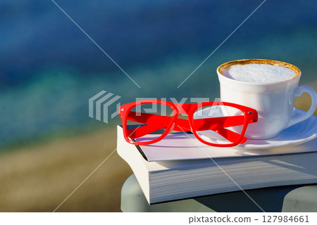 Coffee cup and book on sea coast 127984661