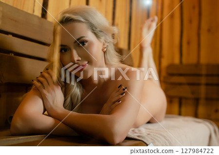 Relaxing woman enjoys a serene moment in a sauna at a spa 127984722
