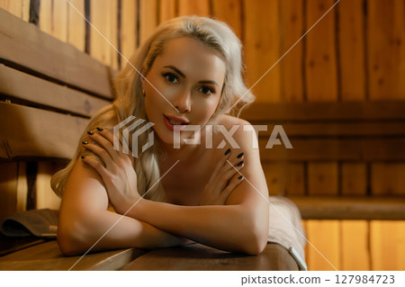 Relaxing woman enjoys a moment of tranquility in a warm sauna environment 127984723