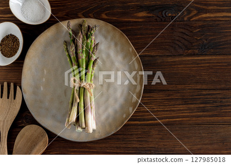 Asparagus spears, salt, pepper, oil and wooden utensils on rustic table. Top view 127985018