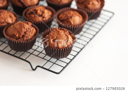 Freshly baked chocolate muffins on a cooling rack. Soft focus 127985026