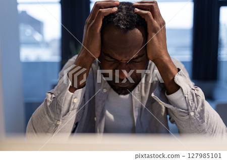 African american man at the laptop looking tired and suffering from a headache African american man at the laptop looking tired and suffering from a headache 127985101