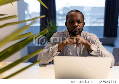African american man at the laptop looking thoughtful and serious 127985114