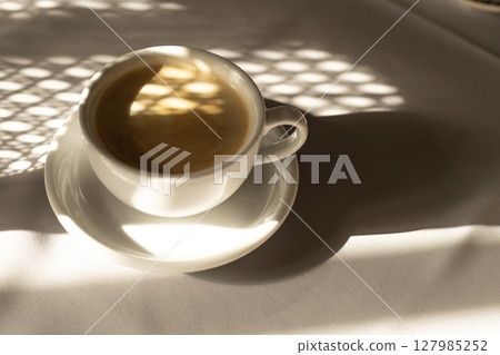 A cup of coffee with milk in the light of the morning sun A cup of coffee with milk in the light of the morning sun 127985252