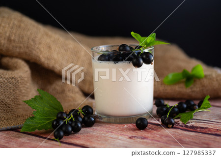 A glass of thick yogurt with currant berries for a healthy diet on a wooden 127985337