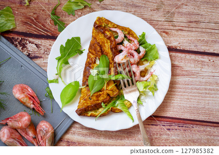 Delicious omelette with shrimps and fresh greens on top Delicious omelette with shrimps and fresh greens on top 127985382