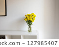 Yellow Chrysanthemums bouquet in transparent glass vase on white modern shelf, minimal interior 127985407