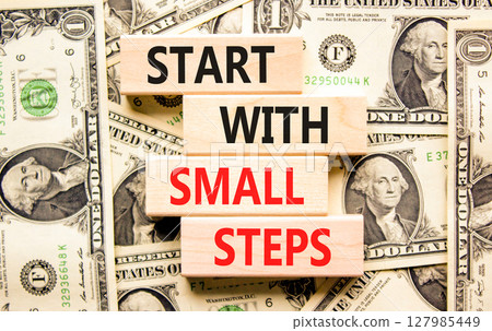 Start with small steps symbol. Concept words phrase Start with small steps on beautiful blocks. Dollar bills. Beautiful dollar bills background. Business Start with small steps concept. Copy space 127985449