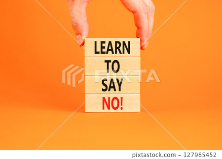 Learn to say no symbol. Concept words phrase Learn to say no on beautiful wooden blocks. Beautiful orange paper background. Businessman's hand Business psychological Learn to say no concept Copy space 127985452
