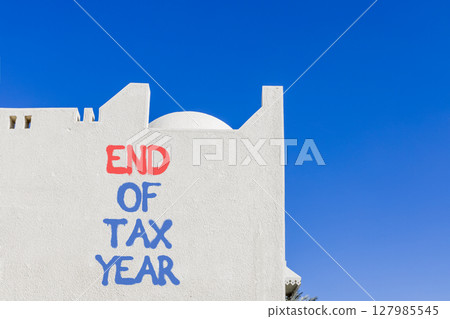 End of tax year symbol. Concept words phrase End of tax year on beautiful white wall. Beautiful white wall and blue sky background. Business End of tax year concept. Copy space. End of tax year symbol. Concept words phrase End of tax year on beautiful white wall. Beautiful white wall and blue sky background. Business End of tax year concept. Copy space. 127985545