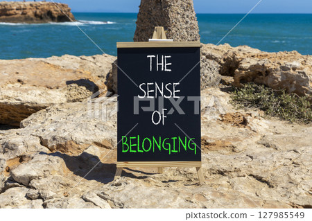 The sense of belonging symbol. Concept words The sense of belonging on beautiful black blackboard. Beautiful stone and blue sea sky background. Business and the sense of belonging concept. Copy space. 127985549