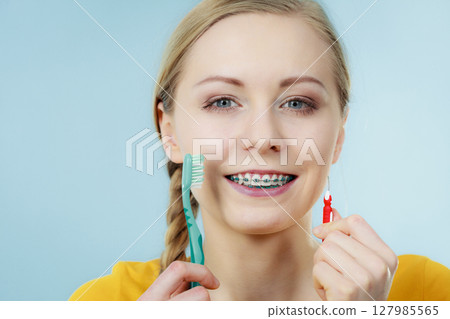 Girl with teeth braces using interdental and traditional brush Girl with teeth braces using interdental and traditional brush 127985565