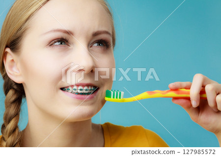 Woman with teeth braces using brush 127985572