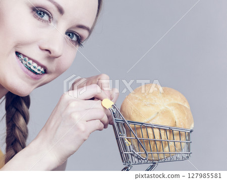 Woman holding shopping cart with bread Woman holding shopping cart with bread 127985581
