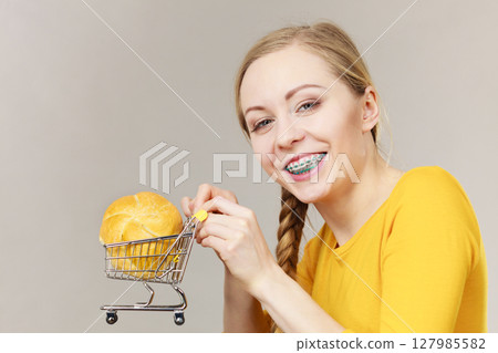 Woman holding shopping cart with bread Woman holding shopping cart with bread 127985582