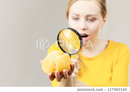 Shocked woman magnifying bun bread roll 127985589