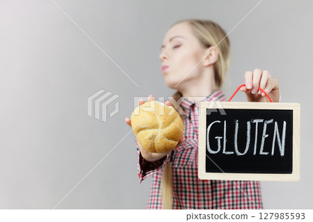 Woman holding board with gluten sign and bun bread Woman holding board with gluten sign and bun bread 127985593