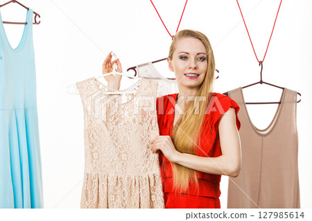 Woman in shop or wardrobe picking dress 127985614
