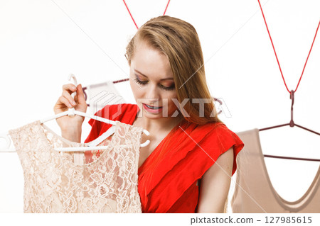 Woman in shop or wardrobe picking dress Woman in shop or wardrobe picking dress 127985615