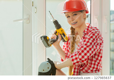 Woman using drill on window Woman using drill on window 127985637