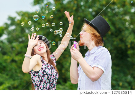 Couple blowing soap bubbles, having fun Couple blowing soap bubbles, having fun 127985814