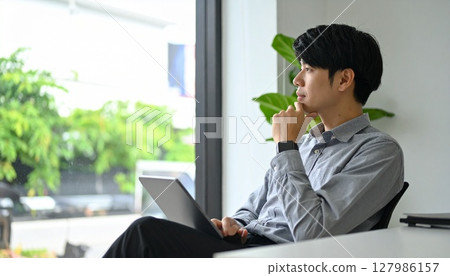 一位商務人士一邊看著平板電腦一邊深入思考 127986157