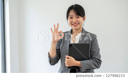 Female business person giving an OK sign 127986215
