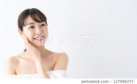 Smiling young woman with hand on cheek 127986255