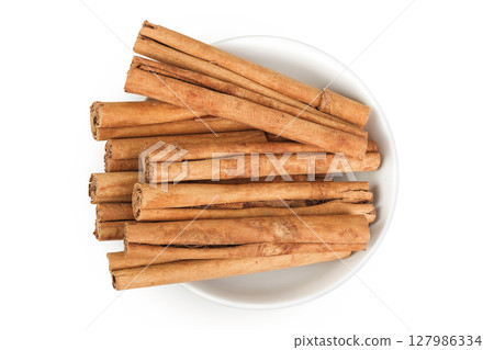 Cinnamon sticks in ceramic bowl isolated on white background with full depth of field. Top view. Flat lay. 127986334