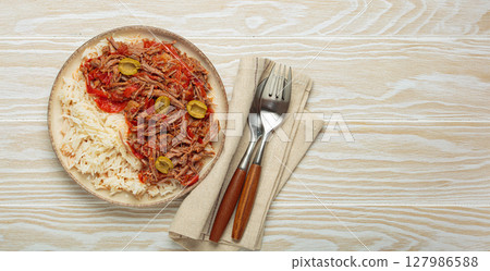 Ropa vieja with white rice, tomato sauce and green olives on a plate top view, traditional dish of Cuba, space for text Ropa vieja with white rice, tomato sauce and green olives on a plate top view, traditional dish of Cuba, space for text 127986588