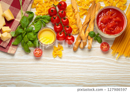 Italian food cuisine background featuring tomato sauce, grissini, pasta, parmesan, fresh basil Italian food cuisine background featuring tomato sauce, grissini, pasta, parmesan, fresh basil 127986597