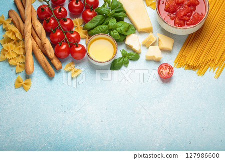 Italian food cuisine background featuring tomato sauce, grissini, pasta, parmesan, fresh basil Italian food cuisine background featuring tomato sauce, grissini, pasta, parmesan, fresh basil 127986600