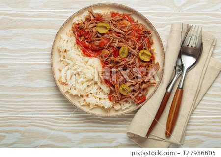 Ropa vieja with white rice, tomato sauce and green olives on a plate top view, traditional dish of Cuba 127986605