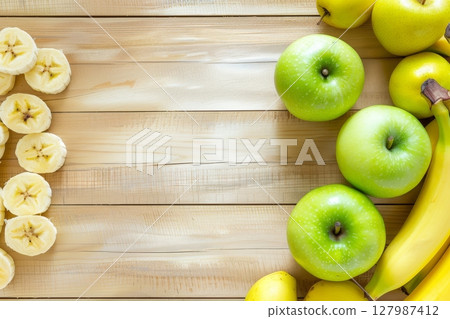 Green apples and yellow bananas are artfully placed on a wooden table, offering a fresh and healthy snack option 127987412