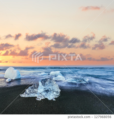 Impressive pieces of the iceberg sparkle on famous Diamond Beach at  Jokulsarlon lagoon during sunset. 127988056