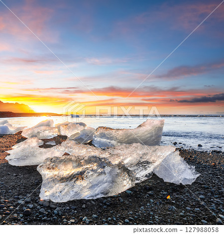 Ramarkable pieces of the iceberg sparkle on famous Diamond Beach at  Jokulsarlon lagoon during sunset. 127988058