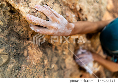 fearlessly climbs up the rock using white magnesia powder, holds her hand to the ledge in the relief, fearlessly climbs up the rock using white magnesia powder, holds her hand to the ledge in the relief, 127988151