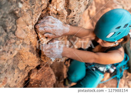 fearlessly climbs up the rock using white magnesia powder, holds her hand to the ledge in the relief, fearlessly climbs up the rock using white magnesia powder, holds her hand to the ledge in the relief, 127988154