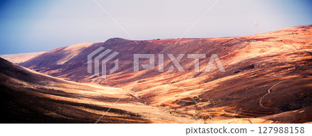 A sandy desert valley, mountains of Canary island in the rays of a sun. A sandy desert valley, mountains of Canary island in the rays of a sun. 127988158
