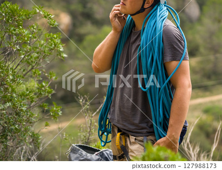 Man with a rope climbing in the mountains. Technical mountaineering. 127988173