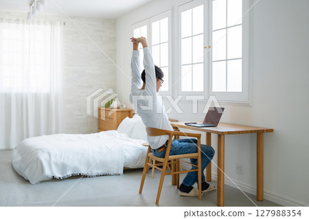 A man who plays a personal computer at home 127988354