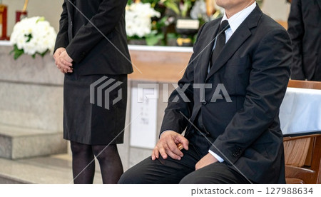 Men and women sitting quietly at a funeral Men and women sitting quietly at a funeral 127988634