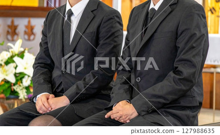Men and women sitting quietly at a funeral Men and women sitting quietly at a funeral 127988635