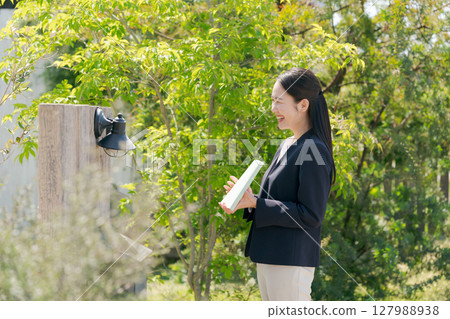 A woman in a suit visiting a house 127988938