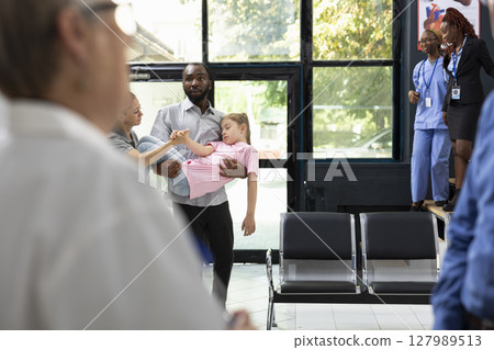 Concerned family members react to unconscious daughter in hospital setting, relying on professional healthcare staff for crisis treatment and urgent life saving attention. Emergency. 127989513