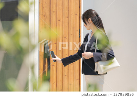 一名穿西裝的女子正在鎖門 一名穿西裝的女子正在鎖門 127989856