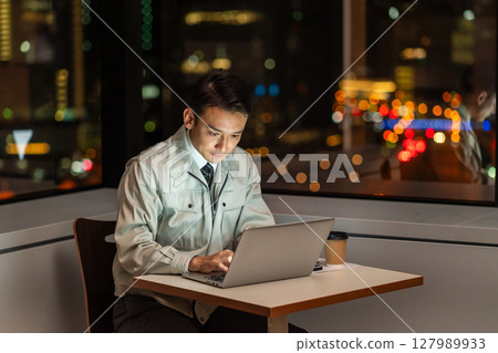 Worker using a computer in an office at night Worker using a computer in an office at night 127989933