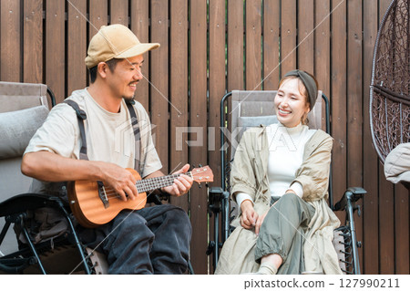 A couple relaxing while playing the ukulele and sitting in a reclining chair A couple relaxing while playing the ukulele and sitting in a reclining chair 127990211